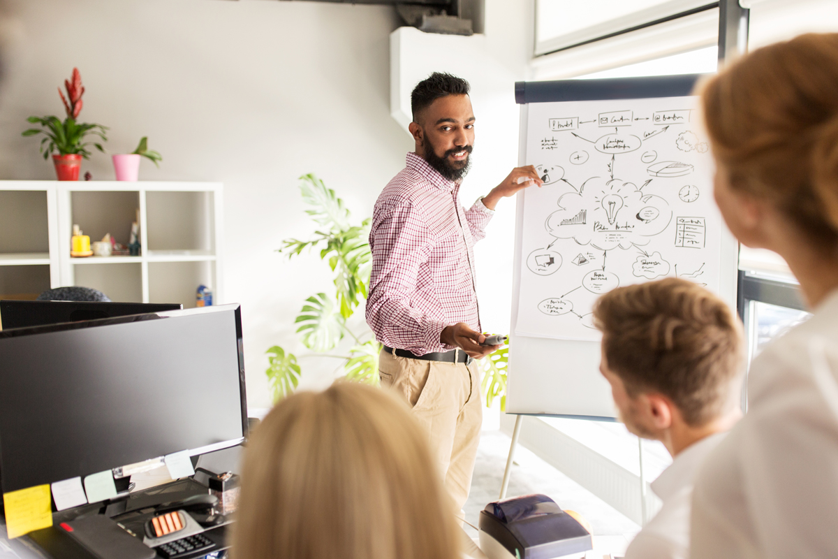 man next to white board teaching others